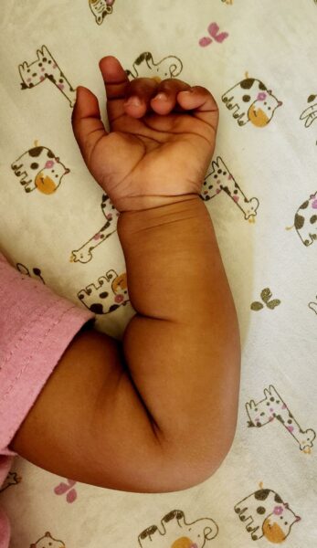 A closeup of the arm of a baby in a bed